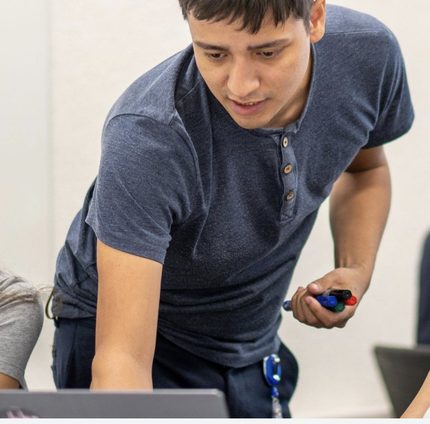 Ausbilder erklärt einer Kursteilnehmerin eine Aufgabe am Laptop